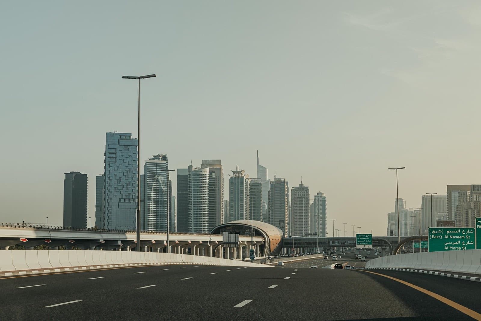 The Dubai skyline seen from Sheikh Zayed Road on a hazy morning, with the metro line running alongside.